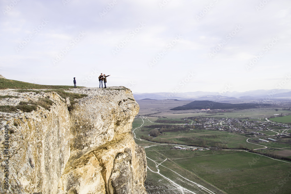 Family with children is on the mountain. White cliff (Ak-Kaya) in the Crimea. Stone blocks and views of the wide steppe. Spring, green grass and clear sky