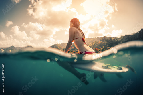 Photography Young woman sitting on surfboard in the ocean