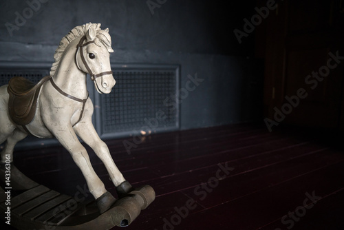 old vintage rocking horse on the background of dark wall. photo