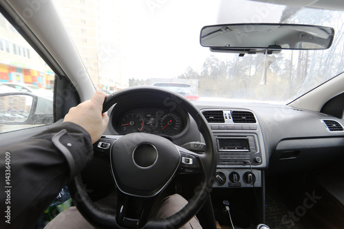 Interior of a car with hands on a steering wheel