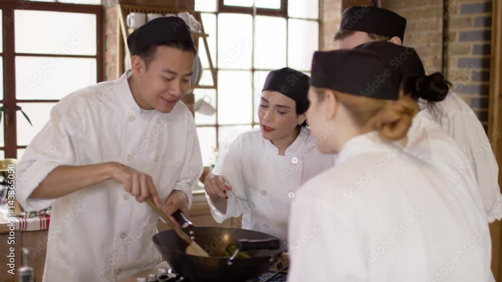 Team of young trainee chefs preparing a meal together in cookery school Team of young trainee chefs preparing a meal together in cookery school