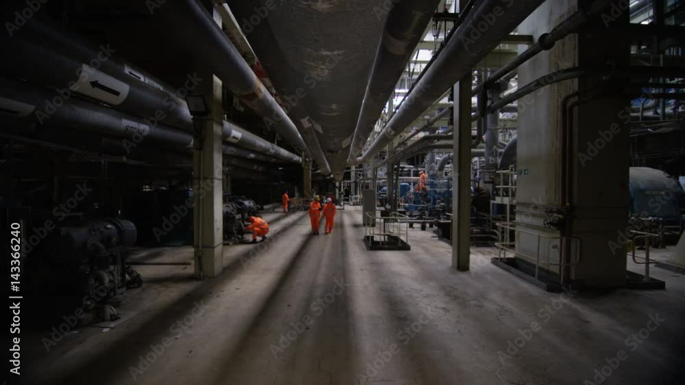 Team of engineers in power station, wide shot of workers & interior structure Team of engineers in power station, wide shot of workers & interior structure