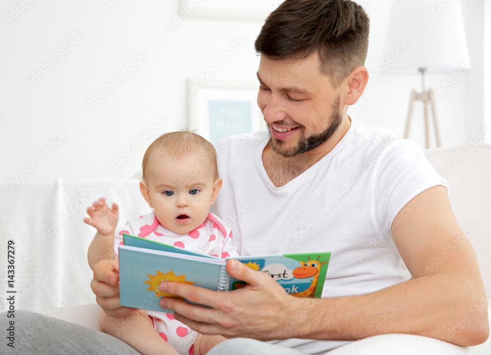 Father showing book to cute baby daughter at home Father showing book to cute baby daughter at home