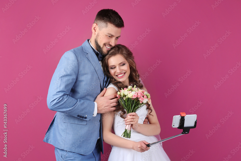 Happy wedding couple making selfie on color background Happy wedding couple making selfie on color background