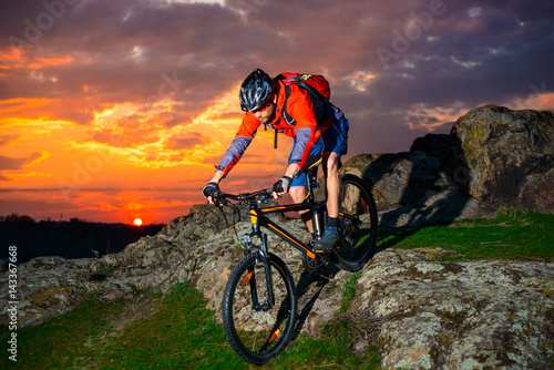 Cyclist Riding Mountain Bike Down Spring Rocky Hill at Beautiful Sunset. Extreme Sports and Adventure Concept. © Maksym Protsenko
