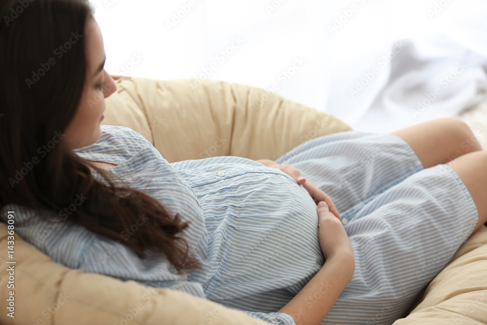 Beautiful pregnant woman sitting on lounge at home Beautiful pregnant woman sitting on lounge at home