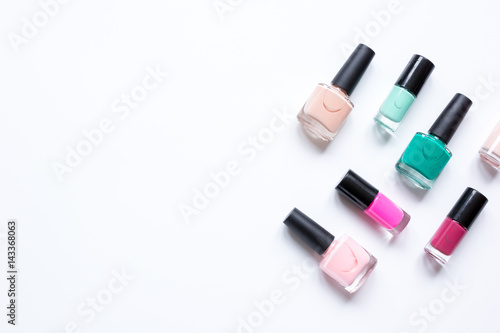 collection of nail polish on white desk background top view mock up