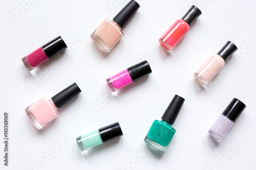 collection of nail polish on white desk background top view pattern