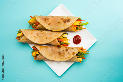 Indian popular snack food called Vegetable spring rolls or veg roll or veg franky made using paneer or cottage cheese and vegetables wrapped inside paratha/chapati/roti with tomato ketchup. photo