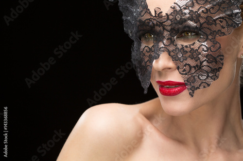 Beautiful woman in a carnival mask on black background
