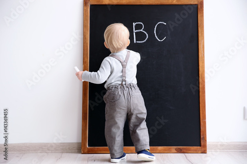 Cute little boy writing on ...