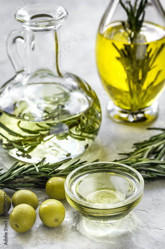 Bottle with olive oil and herbs on stone background