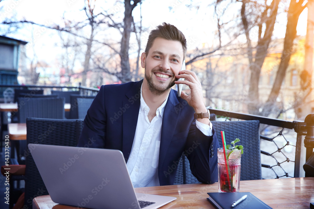Young businessman working with laptop in outdoor cafe Young businessman working with laptop in outdoor cafe
