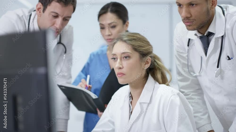Medical team in modern hospital looking at computer & having a meeting Medical team in modern hospital looking at computer & having a meeting