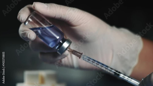 Close up doctor's hand with syringe in ampoule. Drawing of insulin or other medicine into syringe. photo
