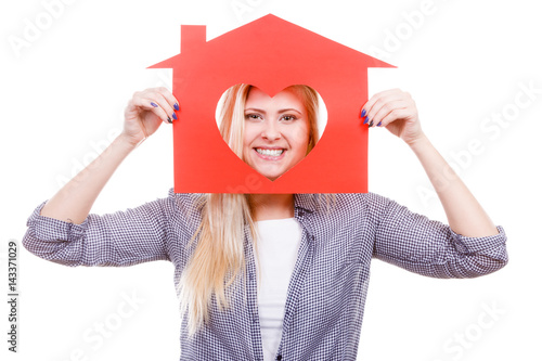 Smiling girl holding red paper house with heart shape
