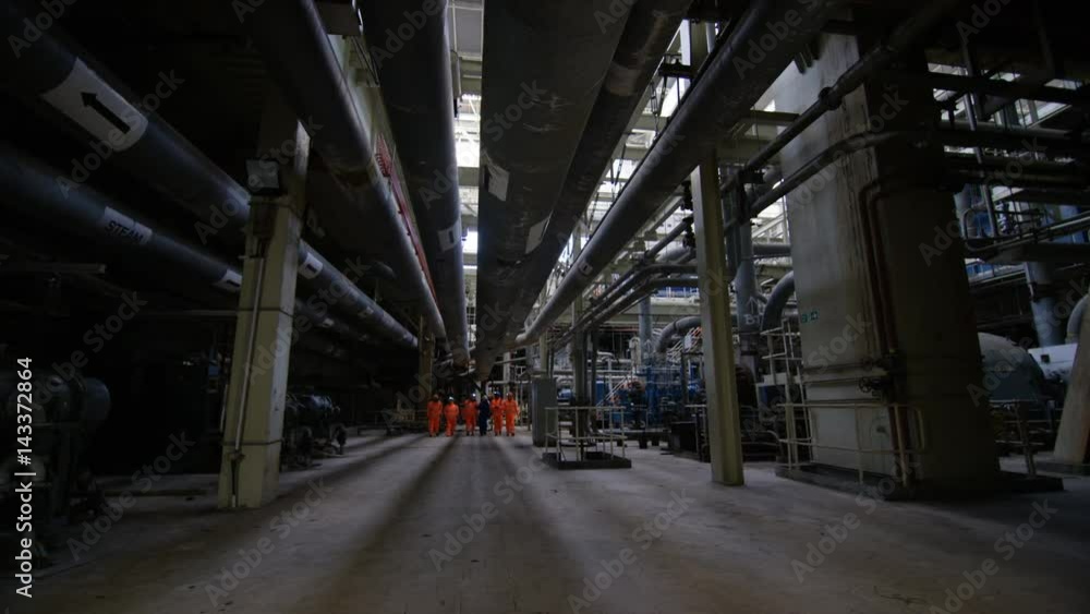Team of engineers in power station, wide shot of workers & interior structure Team of engineers in power station, wide shot of workers & interior structure
