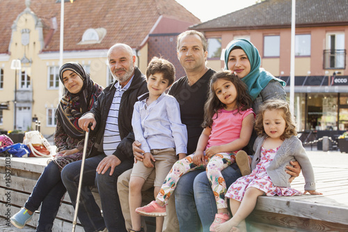 Sweden, Blekinge, Solvesborg, Portrait of family with children (2-3, 4-5, 6-7) sitting on brick wall photo