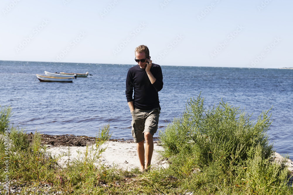 Sweden, Skane, Hollviken, Man talking on phone by sea Sweden, Skane, Hollviken, Man talking on phone by sea