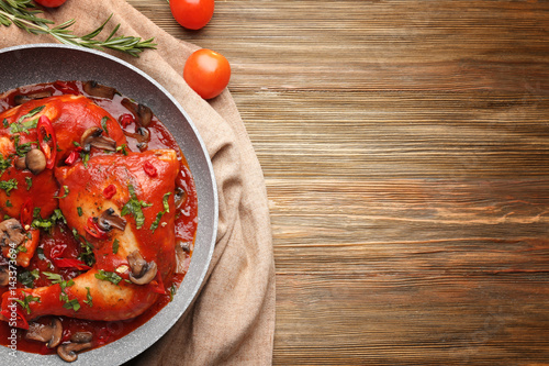 Frying pan with chicken cacciatore on kitchen table photo