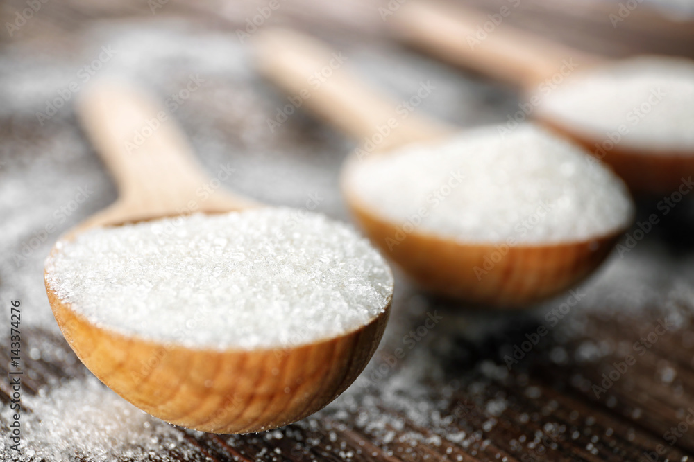 Three spoons with white sugar on wooden background Three spoons with white sugar on wooden background
