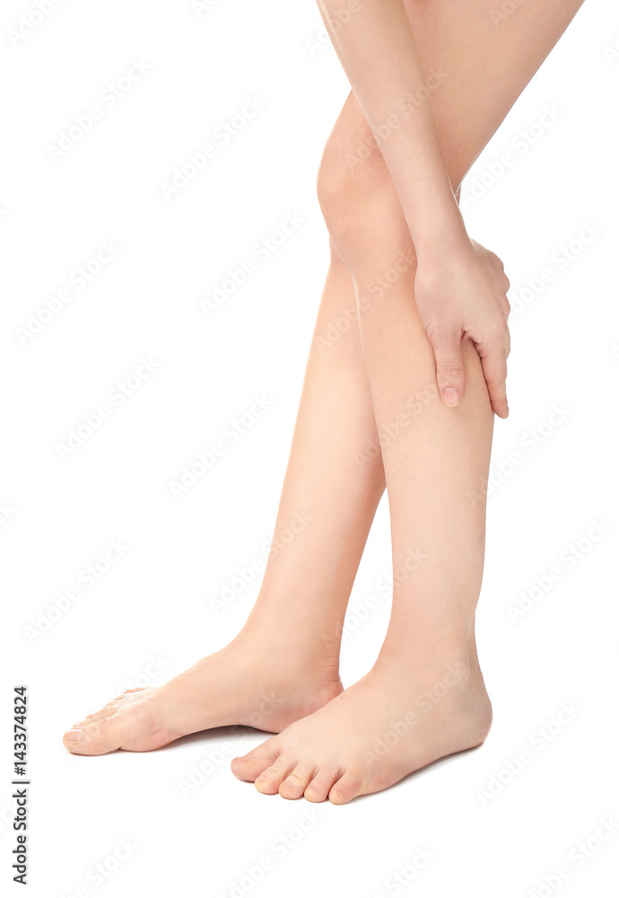 Young woman suffering from pain in legs on white background Young woman suffering from pain in legs on white background