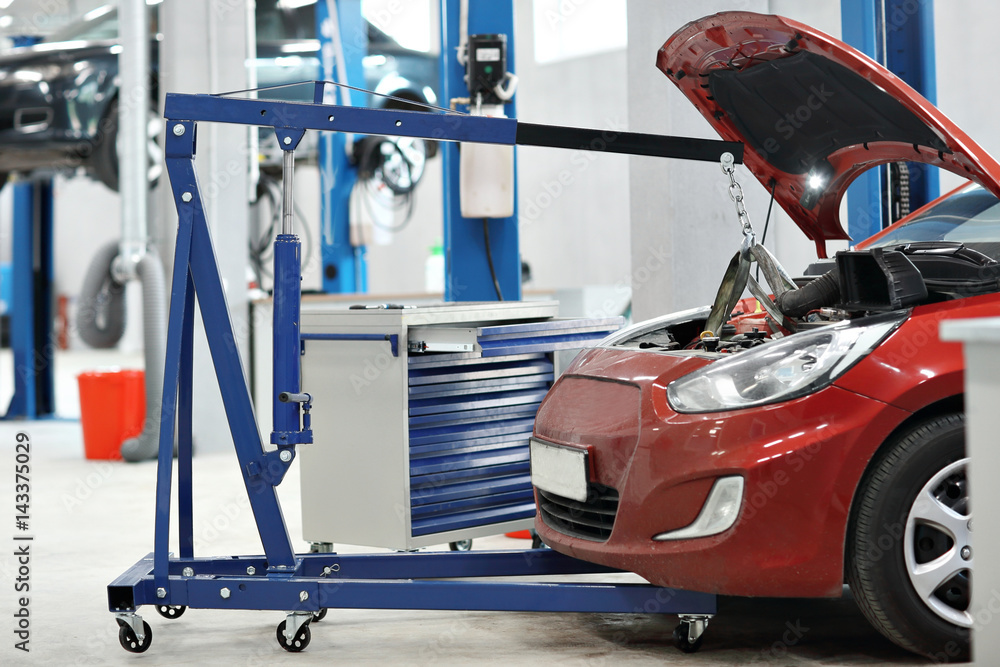 automobile mechanic a crane removed the engine from the car. repairing auto in automobile store automobile mechanic a crane removed the engine from the car. repairing auto in automobile store
