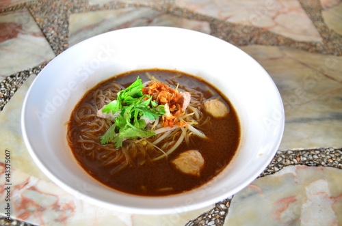 Noodle with pork in white bowl on the table