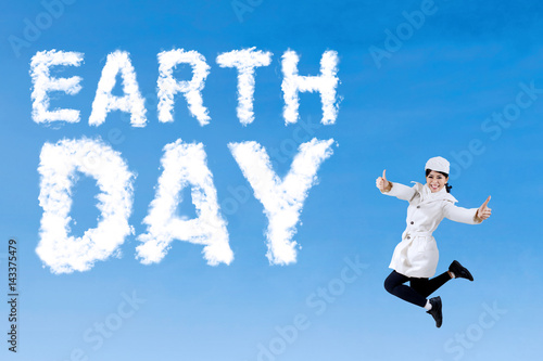 Young woman leaps with Earth Day text © Creativa Images