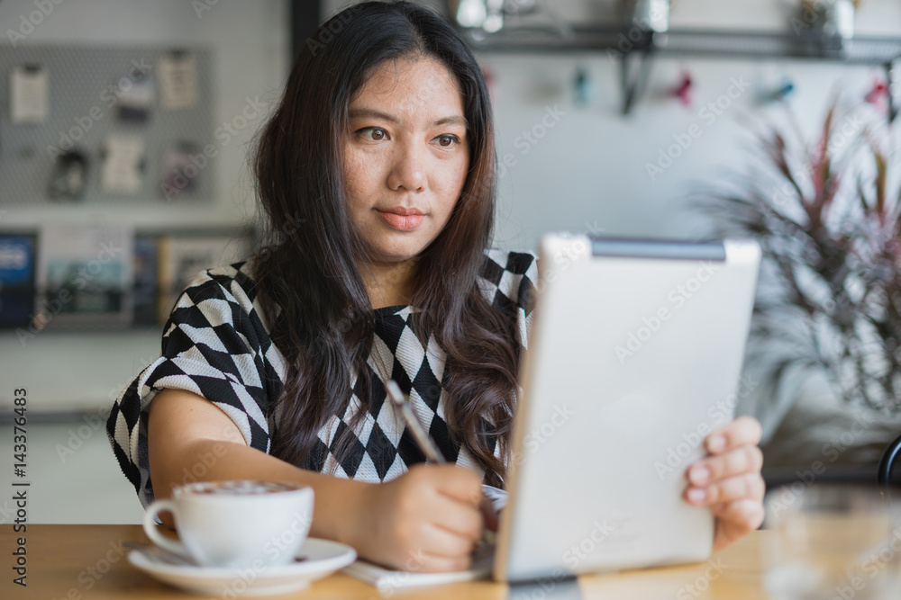 woman tablet work in coffee shop happy face and write on book with hot coffee / woman tablet work woman tablet work in coffee shop happy face and write on book with hot coffee / woman tablet work