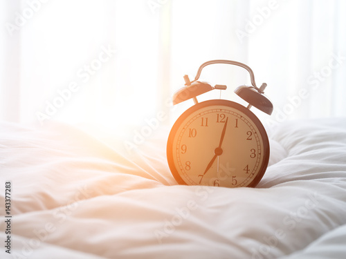 Alarm clock on bed in morning with sun light.. photo