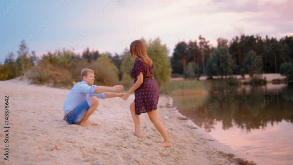 Beautifull Pregnant Woman in Dress Hugging her Husband on the Beach of Lake at Sunset Beautifull Pregnant Woman in Dress Hugging her Husband on the Beach of Lake at Sunset