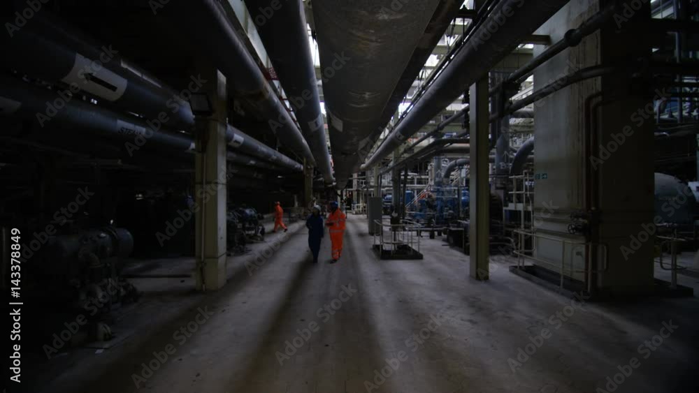 Team of engineers in power station, wide shot of workers & interior structure Team of engineers in power station, wide shot of workers & interior structure