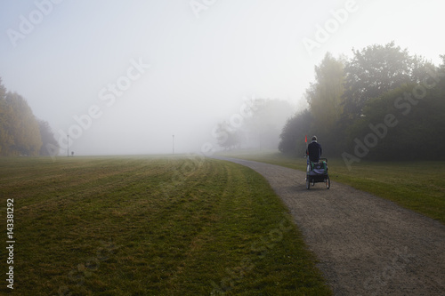 Sweden, Sodermanland, Johanneshov, Nytorps garde, Person cycling on dirt road in fog photo