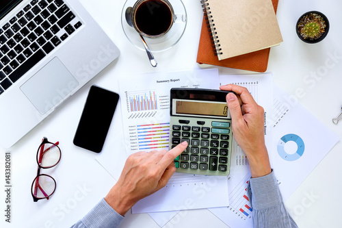 Business man hands working on calculator with financial data on office desk table .View from above.Business analysis and strategy concept. photo