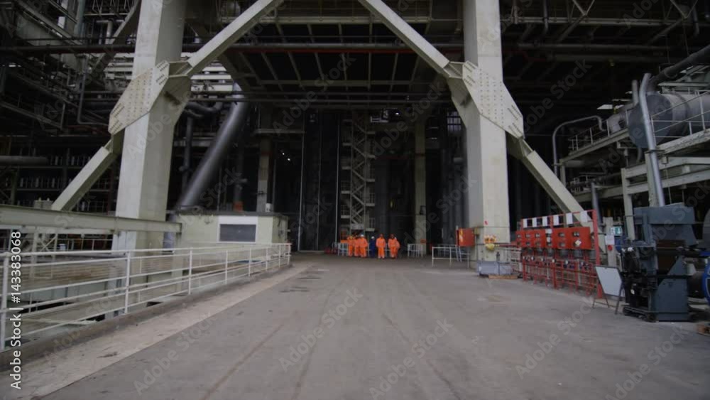 Team of engineers in power station, wide shot of workers & building structure Team of engineers in power station, wide shot of workers & building structure