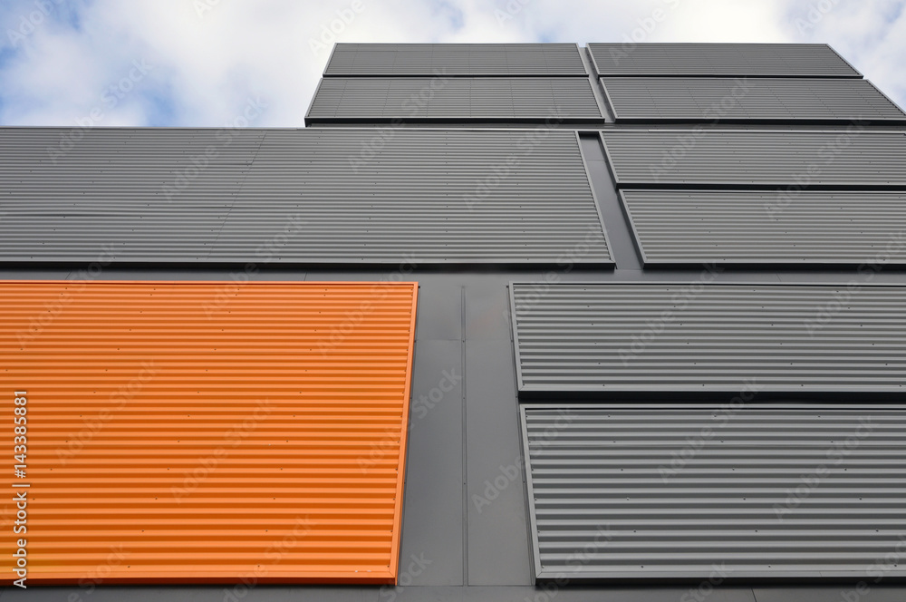 Architectural background. Wall of the modern orange and black corrugated metal panels. Look up.