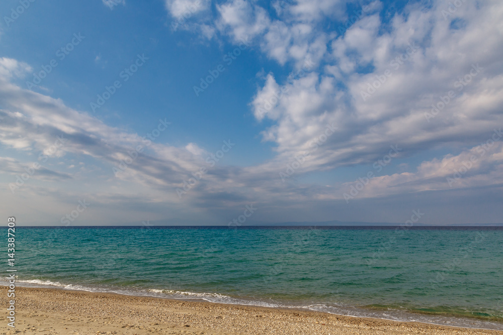 cloudy evening sky on the shore of an undulating turquoise sea in the spring of April.