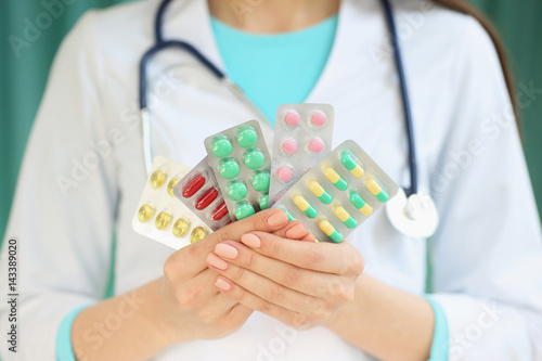 A female doctor holds a plate with pills in her hands. With depth of field image.
