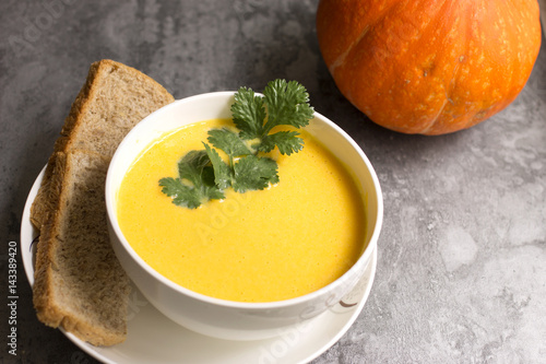 A bowl of pumpkin French soup with bread
