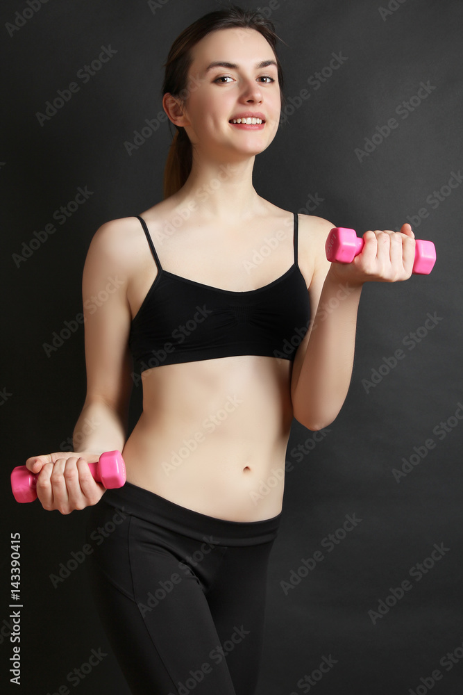 Young girl with dumbbells on a black background. Concept fitness. Young girl with dumbbells on a black background. Concept fitness.