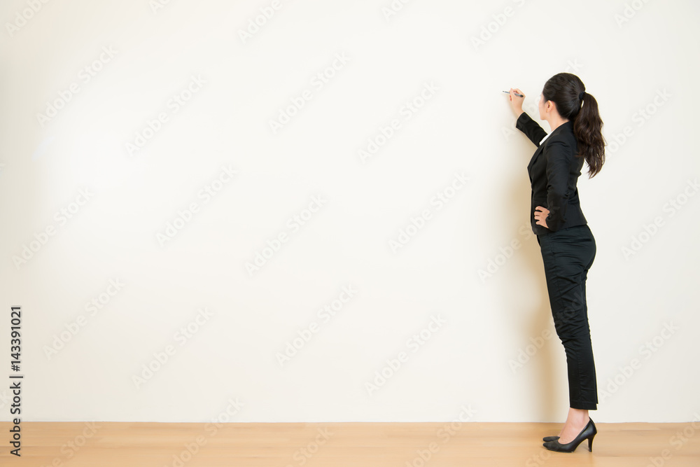 Business woman writing something on white wall Business woman writing something on white wall