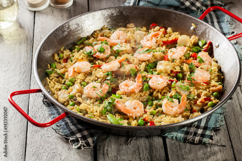 Traditional seafood paella with shrimp, fish and chicken seved in paellera
