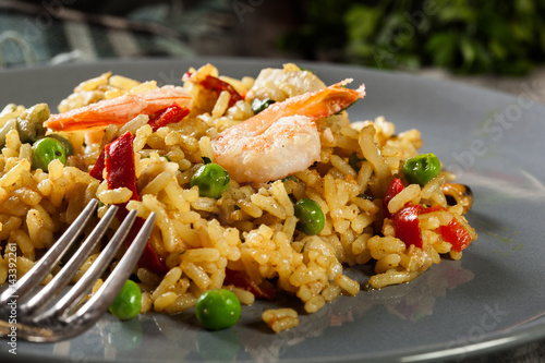 Traditional seafood paella with shrimp, fish and chicken seved in plate.