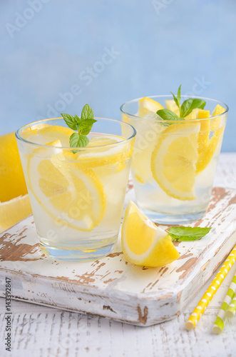 Cold refreshing summer drink with lemon and mint on wooden background. Selective focus, copy space.
