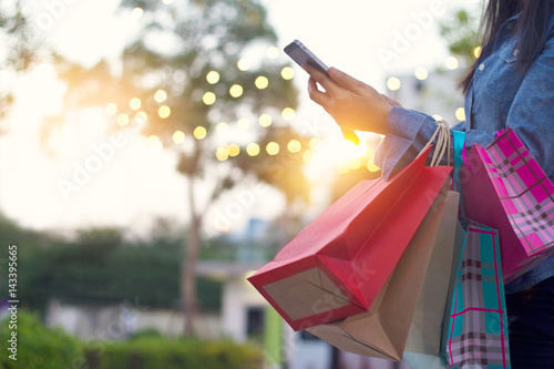 Woman using smartphone with shopping bags in hands