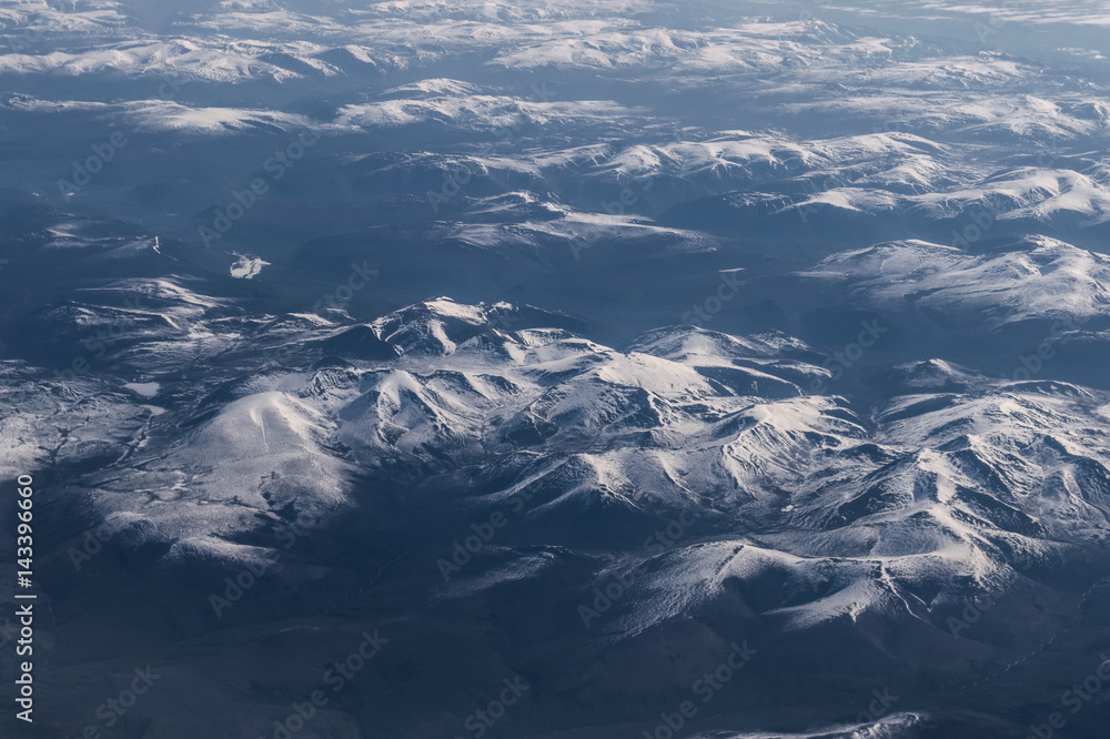 Fototapeta premium View from airplane on Earth surface - snow-capped mountains.