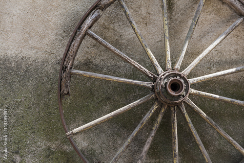 Fotografie Old wagon wheel leaning against the wall.