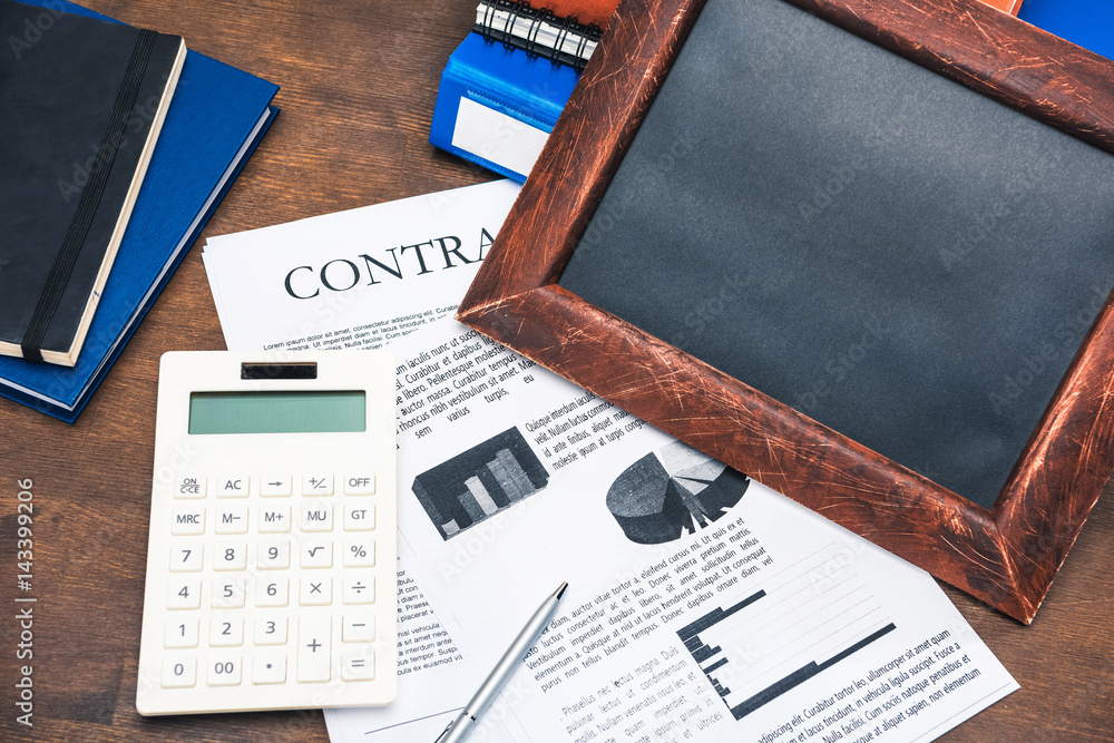 Obraz premium Close-up top view of contract, calculator, business charts and notebooks on wooden table