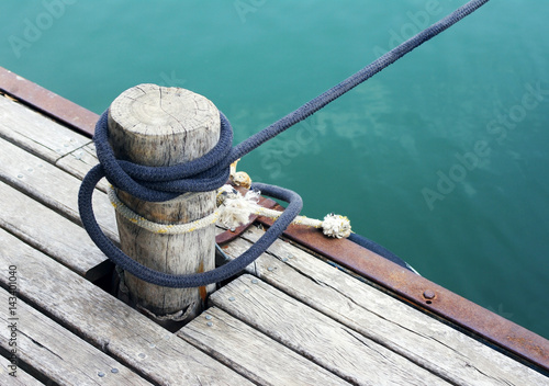 Wood pile with coiled rope on the dock © isavira